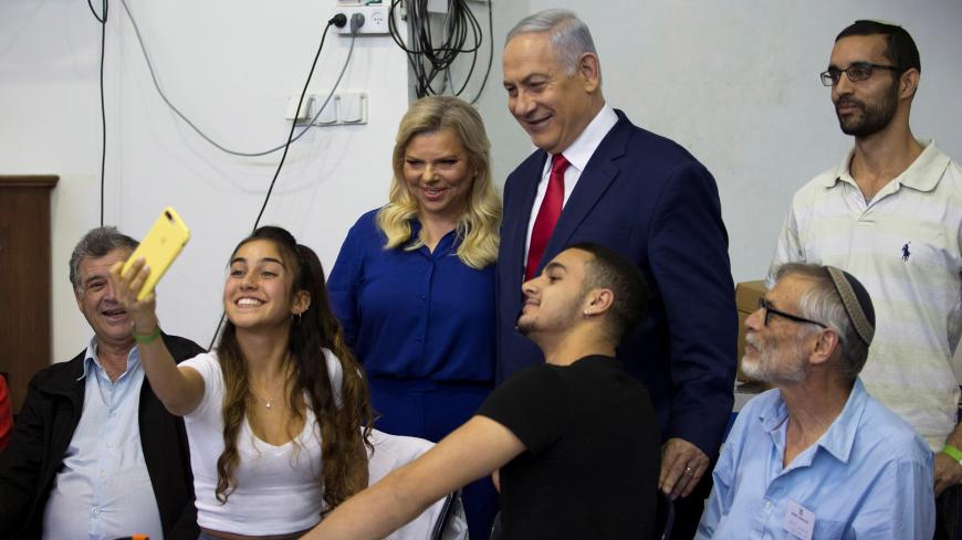 A youth takes a selfie with Israel's Prime Minister Benjamin Netanyahu and his wife Sara after they voted in Israel's parliamentary election in Jerusalem April 9, 2019. Ariel Schalit/Pool via REUTERS  *** Local Caption *** - RC18AF446110