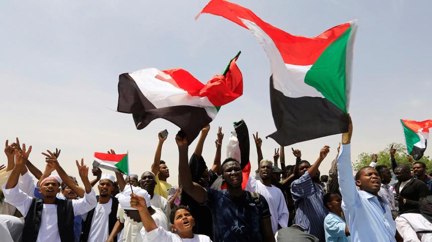 Sudanese demonstrators wave their national flags and chants slogans as they protest against the army's announcement that President Omar al-Bashir would be replaced by a military-led transitional council, near Defence Ministry in Khartoum, Sudan April 12, 2019. REUTERS/Stringer - RC11244C6310