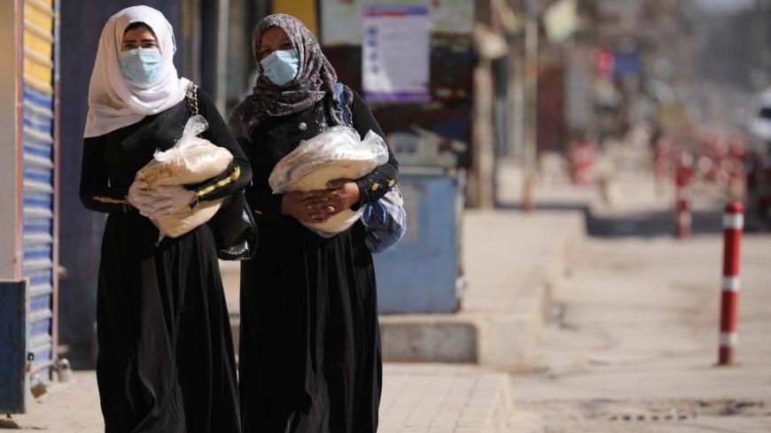 Women hold stacks of bread as they walk along an empty street, as restrictions are imposed as measure to prevent the spread of the coronavirus disease (COVID-19) in Qamishli, Syria March 23, 2020. REUTERS/Rodi Said - RC2VPF9DRWOE