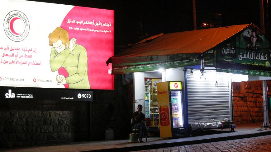 A man sits near a coronavirus awareness billboard, during a lockdown to prevent the spread of coronavirus disease (COVID-19), in Damascus, Syria, April 4, 2020. Picture taken April 4, 2020.  REUTERS/Omar Sanadiki - RC2YXF91PSOD