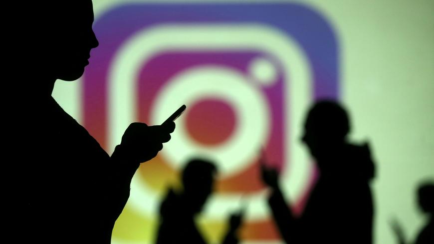 Silhouettes of mobile users are seen next to a screen projection of Instagram logo in this picture illustration taken March 28, 2018.  REUTERS/Dado Ruvic/Illustration - RC1663839A90