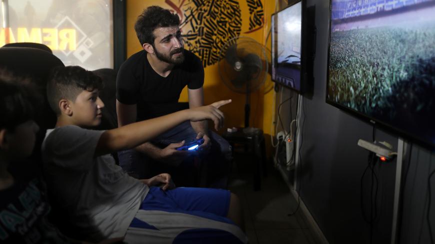 Palestinian rapper Ibrahim Ghunaim (MC Gaza) looks on as a child gestures, at his video game shop in Gaza City, August 16, 2017. REUTERS/Mohammed Salem  SEARCH "SALEM RAPPER" FOR THIS STORY. SEARCH "WIDER IMAGE" FOR ALL STORIES. - RC1123875E80