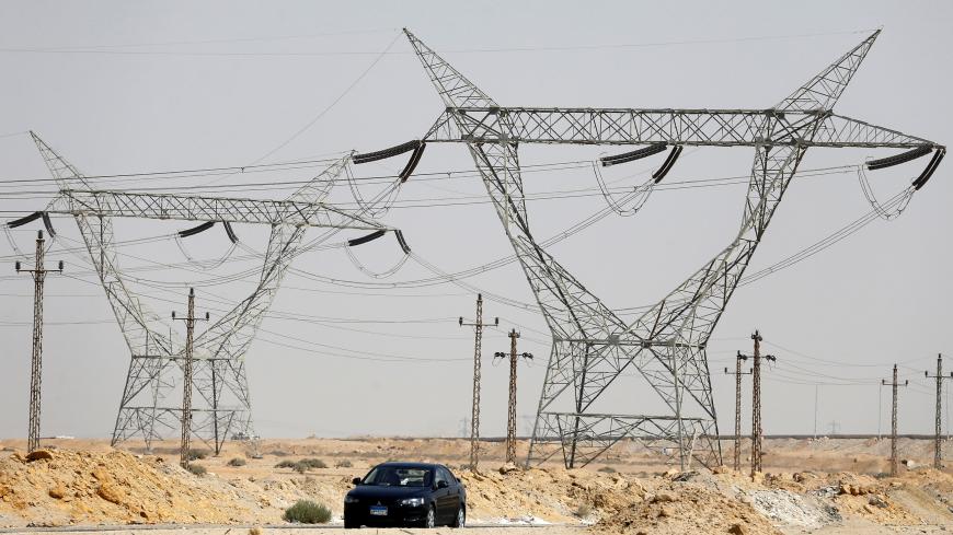 A car passes power lines connecting pylons of high-tension electricity at the highway in Cairo, Egypt August 14, 2017. REUTERS/Amr Abdallah Dalsh - RC122337A6E0