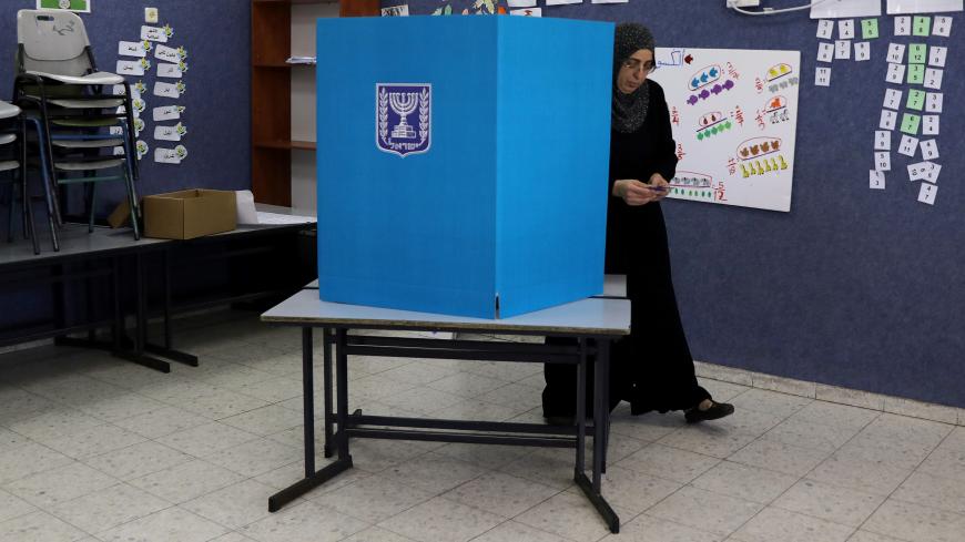 An Israeli-Arab woman walks out from behind a voting booth as Israelis vote in a parliamentary election, at a polling station in Umm al-Fahm, Israel April 9, 2019. REUTERS/Ammar Awad - RC1F60560A00