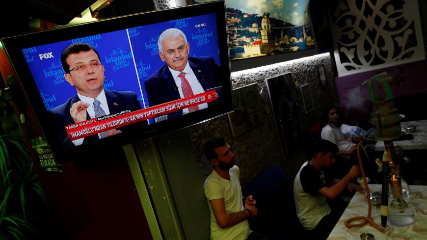 People watch a televised debate between Istanbul's mayoral candidates Ekrem Imamoglu of Republican People's Party (CHP) and Binali Yildirim of AK Party (AKP) at a cafe in central Istanbul, Turkey, June 16, 2019. REUTERS/Murad Sezer - RC12ED04CD00