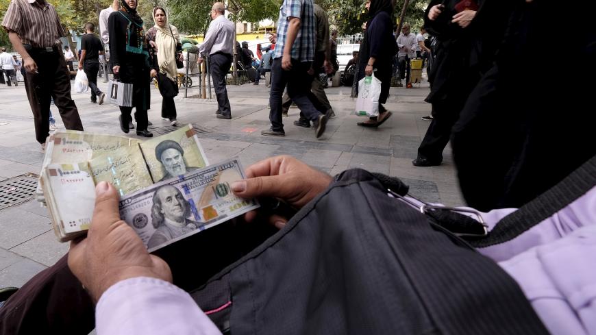 A money changer displays U.S. and Iranian banknotes at the Grand Bazaar in central Tehran October 7, 2015. REUTERS/Raheb Homavandi/TIMA ATTENTION EDITORS - THIS PICTURE WAS PROVIDED BY A THIRD PARTY. REUTERS IS UNABLE TO INDEPENDENTLY VERIFY THE AUTHENTICITY, CONTENT, LOCATION OR DATE OF THIS IMAGE. FOR EDITORIAL USE ONLY. NOT FOR SALE FOR MARKETING OR ADVERTISING CAMPAIGNS. NO THIRD PARTY SALES. NOT FOR USE BY REUTERS THIRD PARTY DISTRIBUTORS. THIS PICTURE IS DISTRIBUTED EXACTLY AS RECEIVED BY REUTERS, AS 