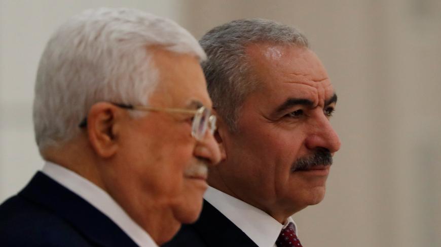 New Palestinian Prime Minister Mohammad Shtayyeh stands next to President Mahmoud Abbas during a swearing in ceremony of a new government, in Ramallah in the Israeli-occupied West Bank April 13, 2019. REUTERS/Mohamad Torokman - RC1F397216C0
