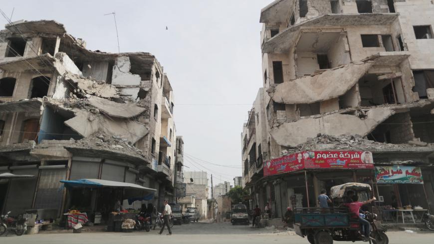 A man walks past damaged buildings in the city of Idlib, Syria May 24, 2019. REUTERS/Khalil Ashawi - RC1D4BDCBD50