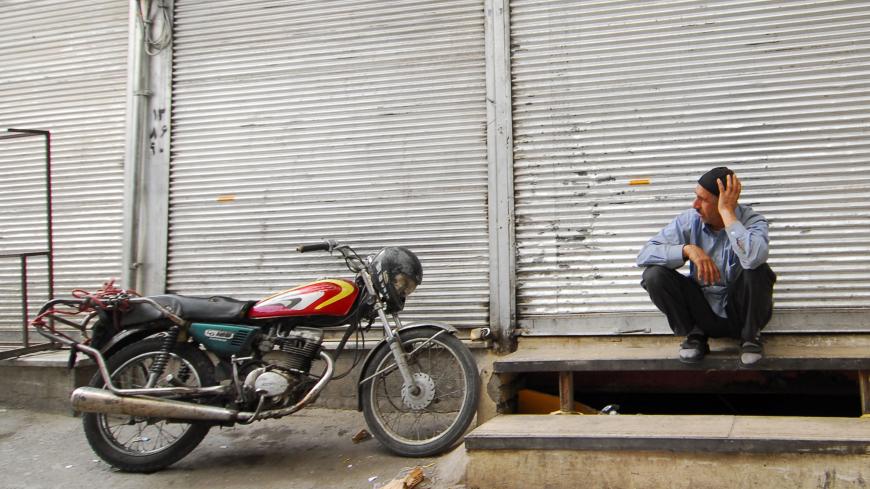 A man sits outside a shop, which was closed as part of a strike, in Tehran's main bazaar October 12, 2008. A week-long strike against a new value added tax (VAT) appeared to be spreading in Tehran's bazaar on Sunday, even though the Iranian government suspended the measure for two months, witnesses said on Sunday.   REUTERS/Stringer (IRAN) - GM1E4AC1M3W01