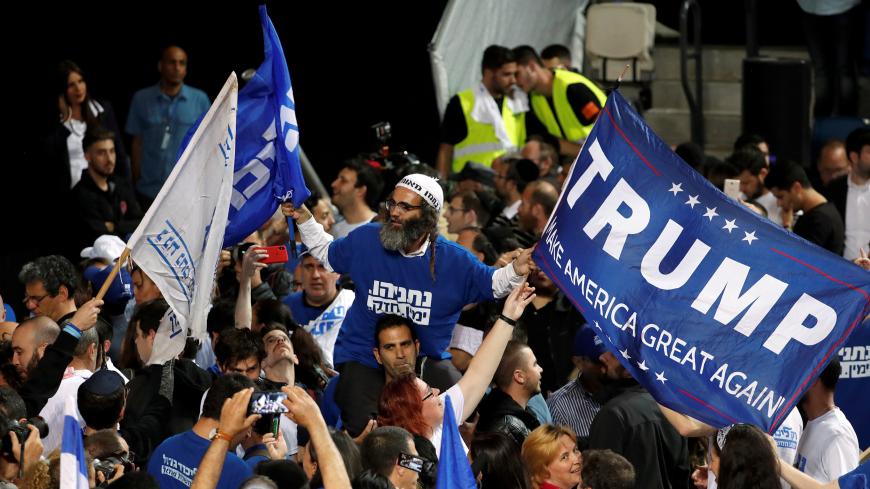 A supporter of Israeli Prime Minister Benjamin Netanyahu's Likud party waves flags, one bearing the name of U.S. President Donald Trump, as the crowd reacts to exit polls in Israel's parliamentary election at the party headquarters in Tel Aviv, Israel April 10, 2019. REUTERS/Ronen Zvulun - RC12929E4A50