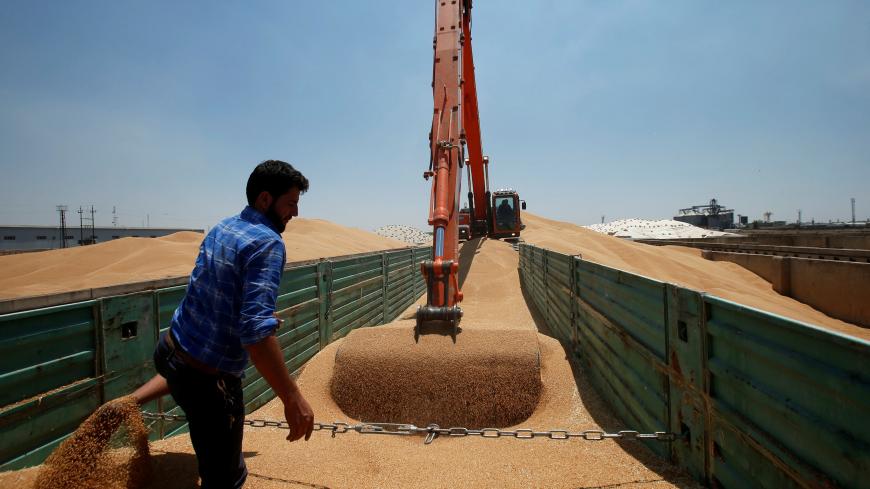 A farmer helps an excavator to unload wheat grain at a silo in Mosul, Iraq June 12, 2019. Picture taken June 12, 2019. REUTERS/Azad Lashkari - RC15C546A580