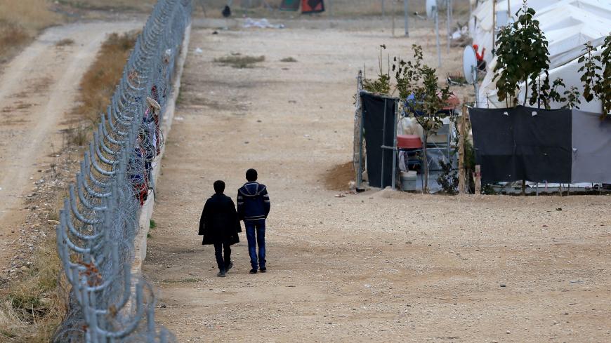 Two Syrian refugees walk along fences in Nizip refugee camp, near the Turkish-Syrian border in Gaziantep province, Turkey, November 30, 2016. REUTERS/Umit Bektas - RC19B9EC1810