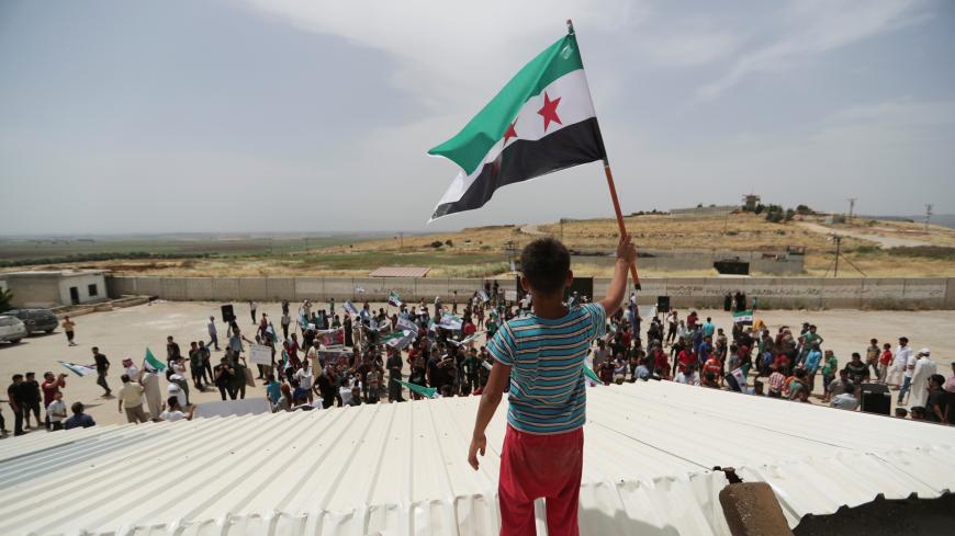 A boy holds the Free Syrian army flag during a protest calling for an end to the strikes and for Ankara to open the frontier at the Atmeh crossing on the Syrian-Turkish border, in Idlib governorate, Syria May 31, 2019. REUTERS/Khalil Ashawi - RC1746D6BD80