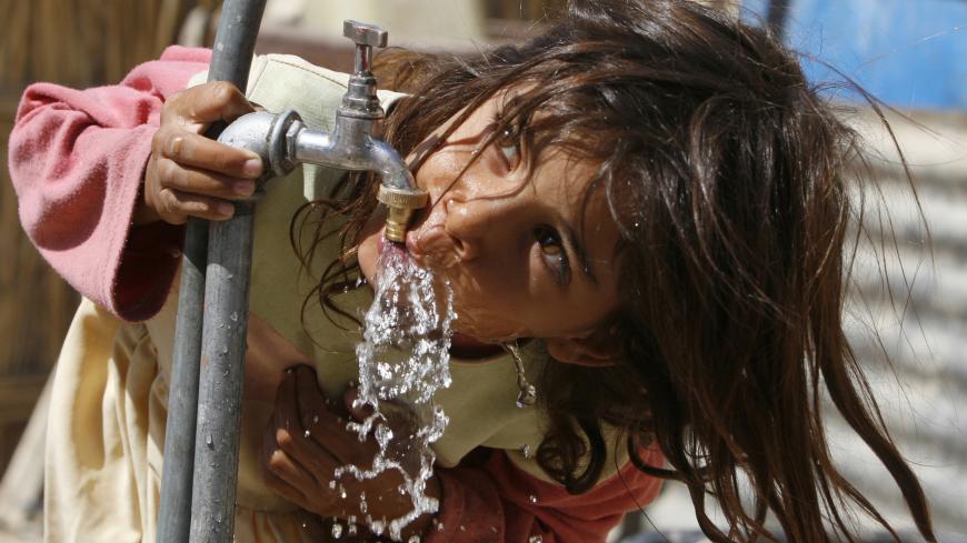 A girl drinks water from a tap inside a refugee camp in Baghdad September 27, 2007. About 70 families lived in a refugee camp after they were displaced from their homes because of the sectarian violence, the Red Crescent organization said.       REUTERS/Mahmoud Raouf Mahmoud (IRAQ) - GM1DWGBBQSAA