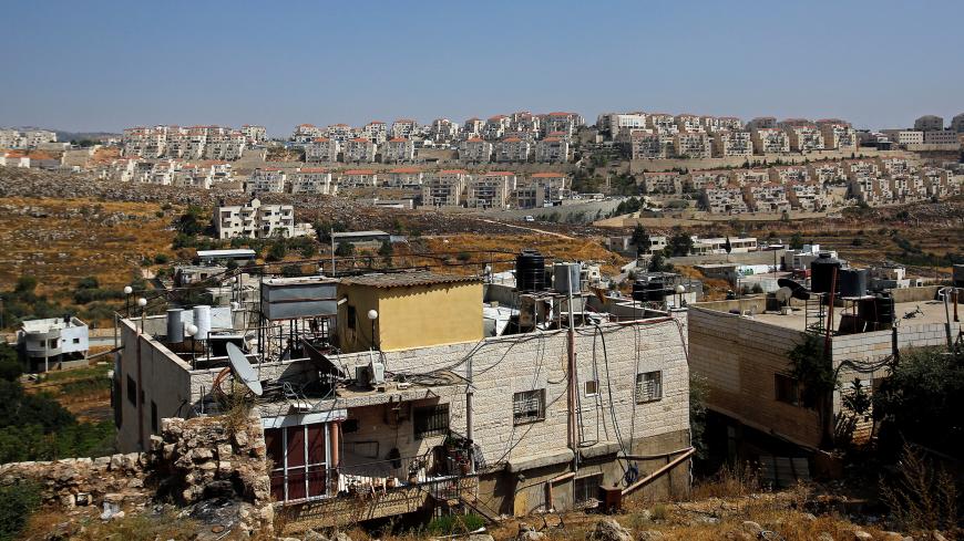 A view shows Palestinian houses in the village of Wadi Fukin as the Jewish settlement of Beitar Illit is seen in the background, in the Israeli-occupied West Bank June 23, 2019. Picture taken June 23, 2019.  REUTERS/Mussa Qawasma - RC1985B332A0