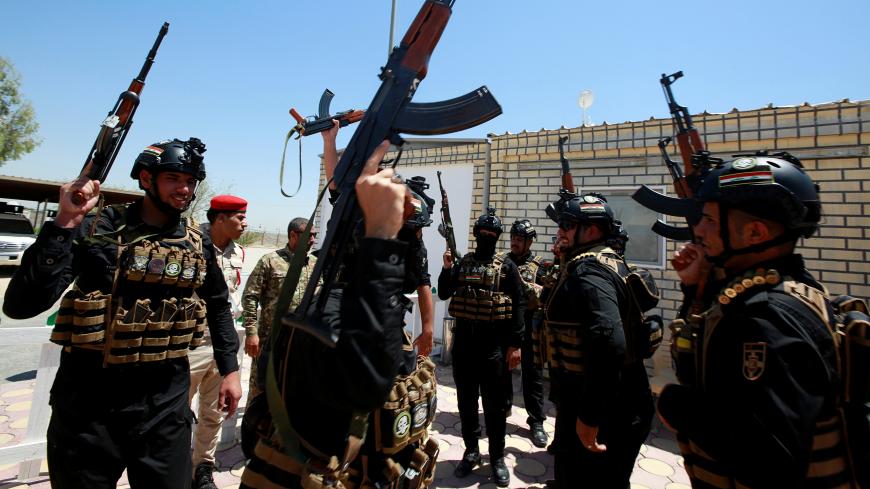 Members of Iraqi Popular Mobilization Forces (PMF) carry their weapons as they shout slogans at their headquarters in the holy city of Najaf, Iraq July 2, 2019. REUTERS/Alaa Al-Marjani - RC1F77CF3350