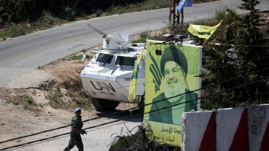 A U.N peacekeepers of the United Nations Interim Force in Lebanon (UNIFIL) walks near a poster depicting Lebanon's Hezbollah leader Sayyed Hassan Nasrallah in Adaisseh, Lebanon  August 26, 2019. REUTERS/Ali Hashisho - RC187080F790