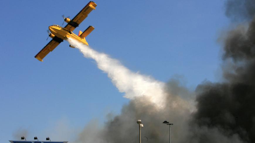 A firefighter plane douses water over the black smoke and flames raging through the cargo section at Ataturk International Airport in Istanbul May 24, 2006. REUTERS/Fatih Saribas - GM1DSRFSRLAA