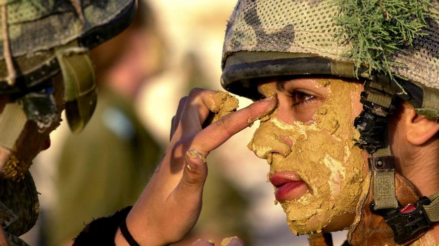 In a picture released on May 23, 2005 by the Israeli Defence Forces shows an Israeli army female soldier painting the face of a comrade with mud prior to a week-long survival course for women in the infantry at an undisclosed location in Israel. REUTERS/IDF/HO  OP/TW - RP6DRMVUMIAA