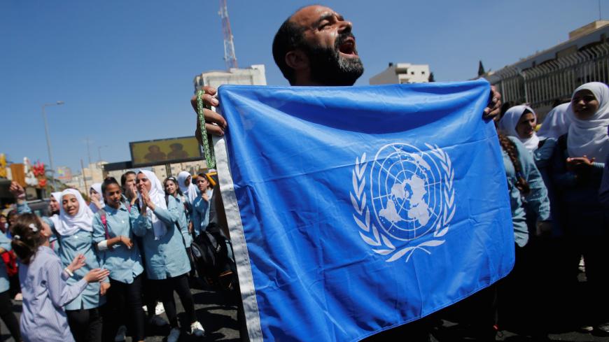 A Palestinian demonstrator holds a United Nations' flag during a rally against a U.S. decision to cut funding to the United Nations Relief and Works Agency (UNRWA) and in support of president Mahmoud Abbas, in Bethlehem in the occupied West Bank September 26, 2018. REUTERS/Mussa Qawasma - RC19AEA408D0