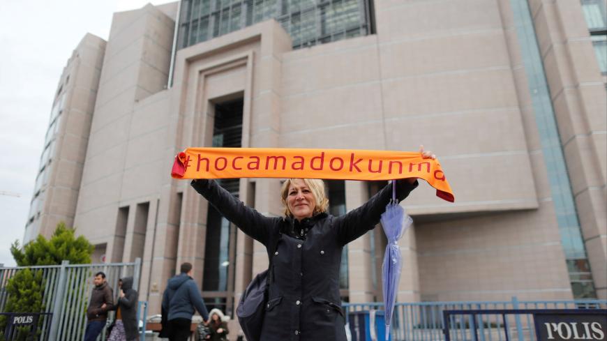 A demonstrator holds scarf reading "Do not touch my Academics" in front of the Justice Palace during first of a series of trials that will begin against a total of some 150 academics from public and private universities accused of spreading terrorist propaganda, in Istanbul, Turkey December 5, 2017. REUTERS/Osman Orsal - RC1A923E7380