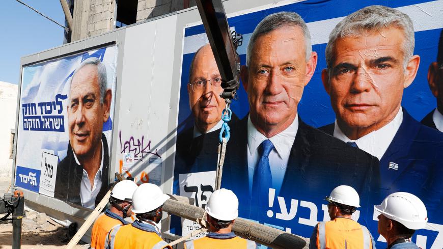 Labourers work in front of electoral campaign posters bearing the portraits of Israel's Prime Minister Benjamin Netanyahu (L), leader of the Likud party, and retired Israeli general Benny Gantz (R), one of the leaders of the Blue and White (Kahol Lavan) political alliance, in the Israeli city of Tel Aviv, on April 3, 2019, ahead of the general election scheduled for April 9. (Photo by JACK GUEZ / AFP)        (Photo credit should read JACK GUEZ/AFP/Getty Images)