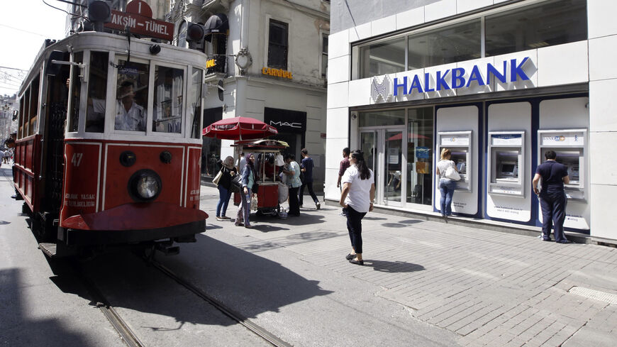 Customers use automated teller machines at a branch of Halkbank as a tram drives by in Istanbul August 15, 2014. Turkey's state-run lender Halkbank said on Friday it has offer to buy a 76.76 percent stake in Serbian lender Cacanska Banka for an undisclosed sum. Halkbank offered no further details on the potential acquisition in a statement to the Istanbul stock exchange. REUTERS/Osman Orsal (TURKEY - Tags: BUSINESS) - GM1EA8F1N2P01