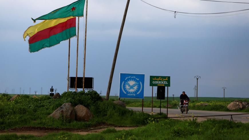 A man rides on a motorbike past a Kurdish female fighters of the Women's Protection Unit (YPJ) flag in the town of Rmeilan, Hasaka province, Syria March 28, 2019. Picture taken March 28, 2019. REUTERS/Ali Hashisho - RC1B20B29D90