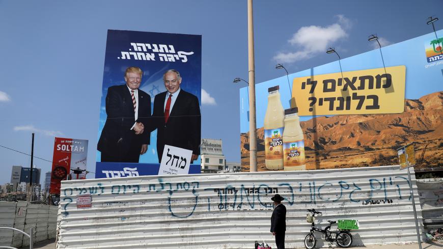 An ultra-Orthodox Jewish man stands next to a Likud party election campaign banner depicting Israeli Prime Minister Benjamin Netanyahu and U.S. President Donald Trump in Bnei Brak, Israel September 9, 2019. The words in Hebrew read, "Netanyahu, a different league" REUTERS/Ammar Awad - RC1F7BD95F00