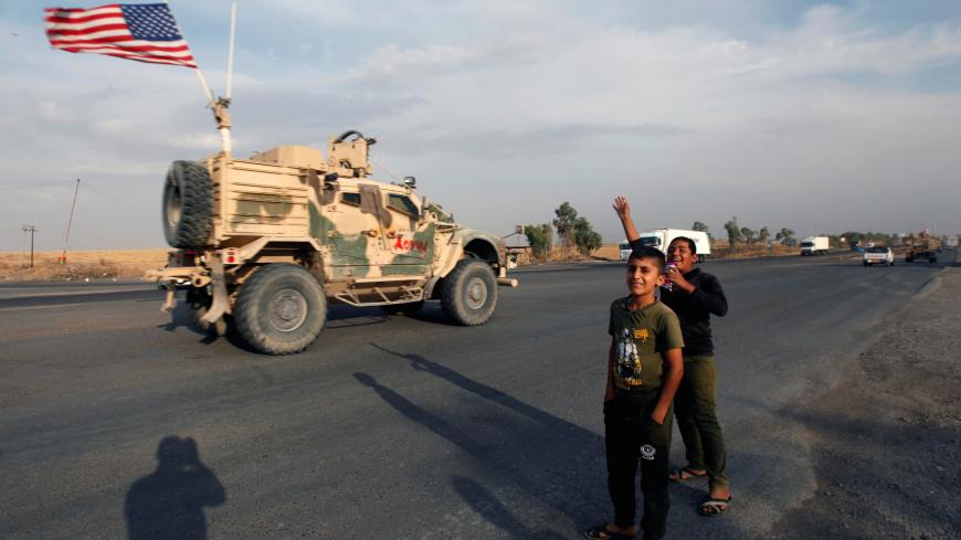 Boys wave towards a convoy of U.S. vehicles withdrawing from northern Syria, in Erbil, Iraq October 21, 2019. REUTERS/Azad Lashkari - RC155923AC50