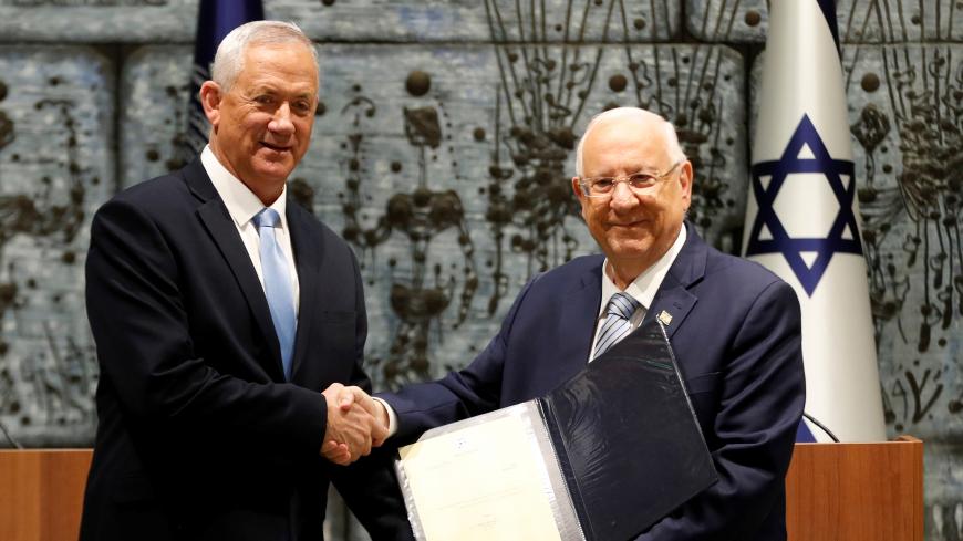 Israeli President Reuven Rivlin gives Benny Gantz, leader of Blue and White party, a file during a nomination ceremony at the President's residency in Jerusalem October 23, 2019 REUTERS/ Ronen Zvulun - RC1981876F70