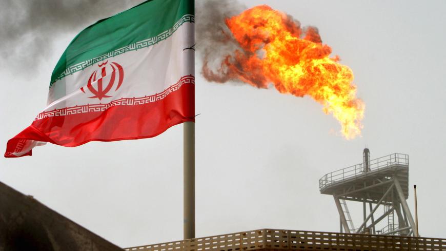 A gas flare on an oil production platform in the Soroush oil fields is seen alongside an Iranian flag in the Gulf July 25, 2005. REUTERS/Raheb Homavandi/File Photo   - S1BEUBPCZPAB