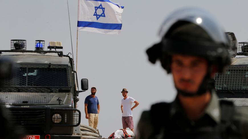 Israeli settler look at Palestinian demonstrators during a protest against Jewish settlements, in  Al-Sawaherh in the Israeli-occupied West Bank September 20, 2019. REUTERS/Mussa Qawasma - RC1C30A9A8D0