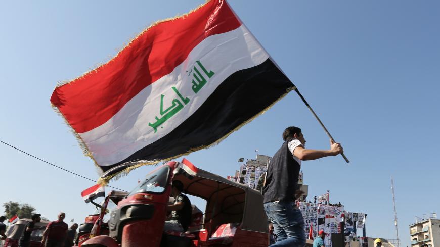 An Iraqi protester waves the natioanl flag in Tahrir square in the capital Baghdad on November 5, 2019, amid ongoing anti government demonstrations. - Iraqi security forces fired live rounds yesterday at protesters in Baghdad, after four demonstrators were shot dead overnight outside the Iranian consulate in the holy city of Karbala. (Photo by SABAH ARAR / AFP) (Photo by SABAH ARAR/AFP via Getty Images)