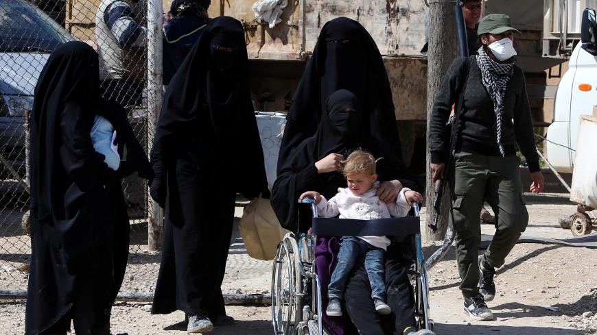 The wife of an Islamic State militant sits in a wheelchair with her son on her lap at al-Hol displacement camp in Hasaka governorate, Syria, April 1, 2019. REUTERS/Ali Hashisho - RC14C2BF54A0