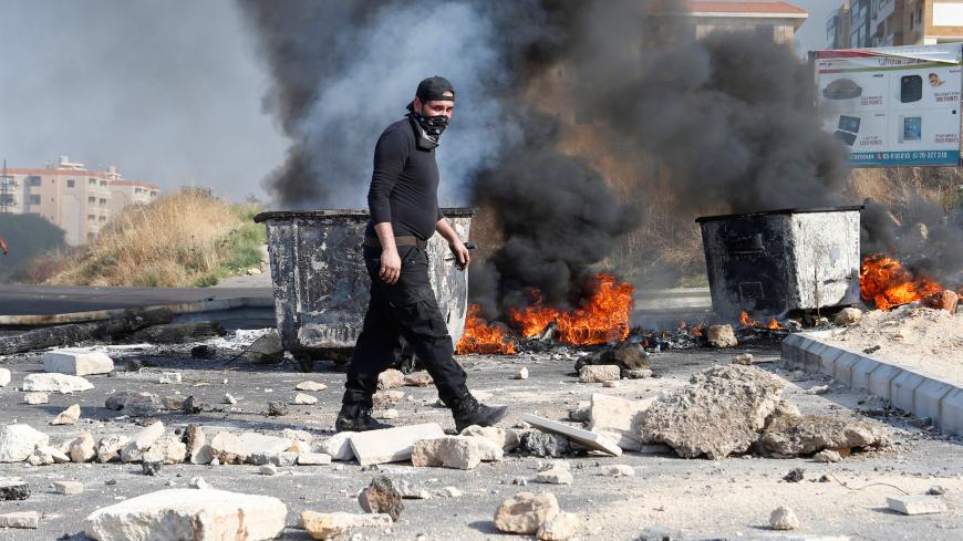 A demonstrator walks near burning tires barricading a road during ongoing anti-government protests in Khaldeh, Lebanon November 13, 2019. REUTERS/Mohamed Azakir - RC2AAD9QIKO5