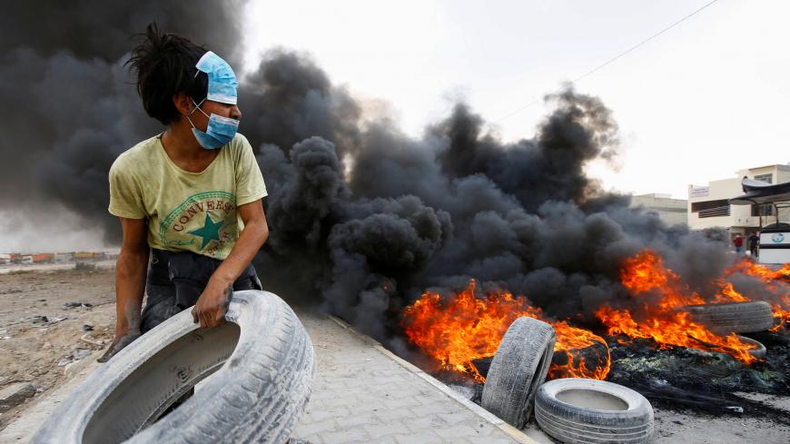 An Iraqi demonstrator burns tires during the ongoing anti-government protests in Najaf, Iraq November 18, 2019. REUTERS/Alaa al-Marjani - RC2ODD964QFI