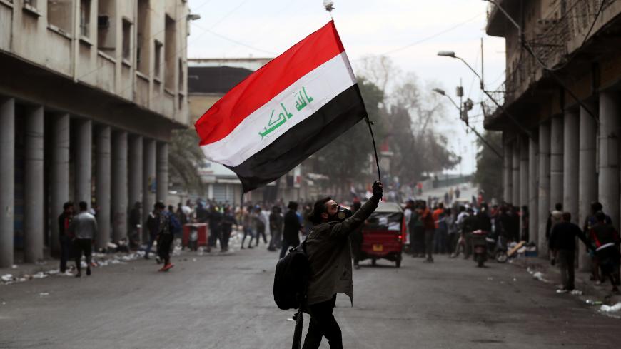 An Iraqi demonstrator carries an Iraqi flag during the ongoing anti-government protests in Baghdad, Iraq November 27, 2019. REUTERS/Thaier al-Sudani - RC2RJD9KYCGH
