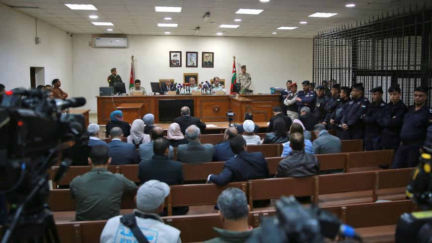 Israeli Konstantin Kotov stands in the defendants's cage next to a translator (R) during his trial in Amman on December 2, 2019. - Kotov,  was arrested in neighbouring Jordan a month ago, is on trial for "illegal entry into the territory of the kingdom (Jordan) and possession of drugs for consumption," officials said. Illegal entry into Jordan is punishable by up to one year in prison, while possession of drugs carries a penalty of up to three. Kotov's arrest comes amid a cooling of ties between Israel and 