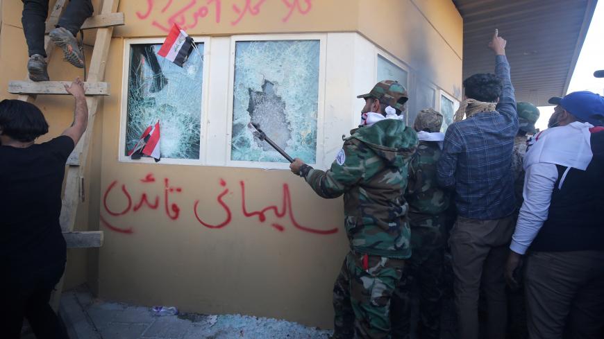 Iraqi protesters, including members the Hashed al-Shaabi, a mostly Shiite network of local armed groups trained and armed by powerful neighbour Iran, smash the bullet-proof glass of the US embassy's windows in Baghdad after breaching the outer wall of the diplomatic mission on December 31, 2019 to vent their anger over weekend air strikes that killed pro-Iran fighters in western Iraq. - It was the first time in years protesters have been able to reach the US embassy in the Iraqi capital, which is sheltered 
