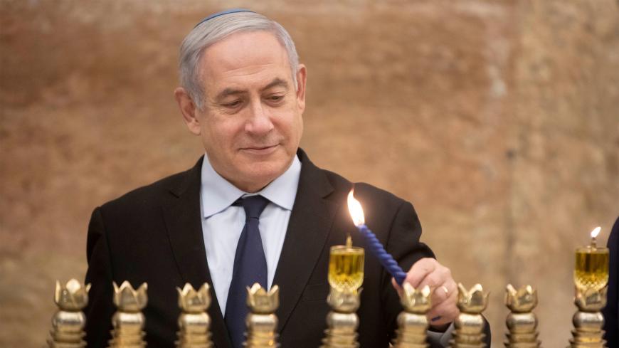 Israeli Prime Minister Benjamin Netanyahu, lights a Hanukkah candle at the Western Wall, the holiest site where Jews can pray in Jerusalem's old city, December 22, 2019. Sebastian Scheiner/Pool via REUTERS - RC2I0E9514H5