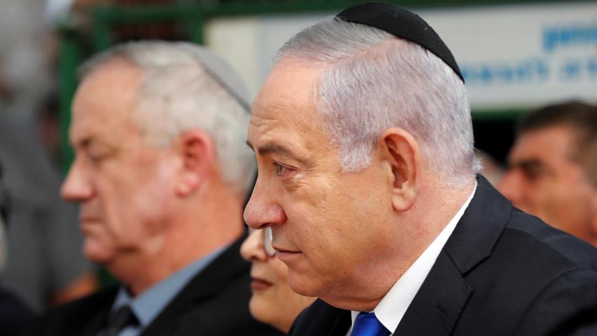 Israeli Prime Minister Benjamin Netanyahu looks on as he sits next to Benny Gantz, leader of Blue and White party, during a memorial ceremony for late Israeli President Shimon Peres, at Mount Herzl in Jerusalem September 19, 2019. REUTERS/Ronen Zvulun - RC140183F6E0
