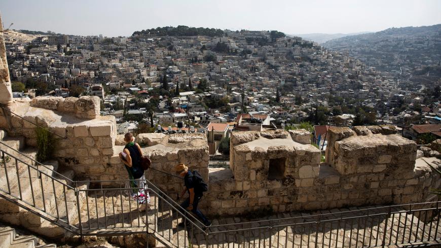 The Palestinian neighborhood of Silwan is seen in the background as people walk on a promenade on the surrounding walls of Jerusalem's Old City November 7, 2019. REUTERS/Ronen Zvulun - RC2F6D9MOPO2