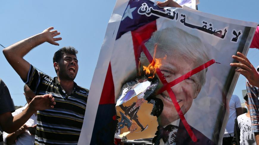 Palestinian demonstrators burn a crossed-out poster depicting U.S. President Donald Trump and reading: "no for Deal of the Century" during a protest against Bahrain's workshop for U.S. Middle East peace plan, in the southern Gaza Strip, June 26, 2019. REUTERS/Ibraheem Abu Mustafa - RC1478E53560