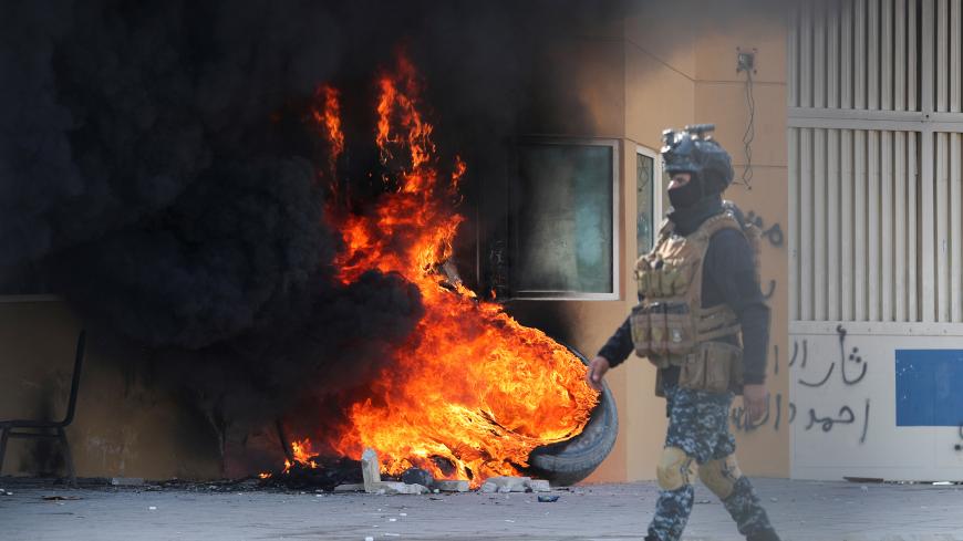 A member of Iraqi security forces walks near burning tyres at the reception room of the U.S. Embassy, during a protest to condemn air strikes on bases belonging to Hashd al-Shaabi (paramilitary forces), in Baghdad, Iraq January 1, 2020. REUTERS/Thaier al-Sudani     TPX IMAGES OF THE DAY - RC207E9KASMJ