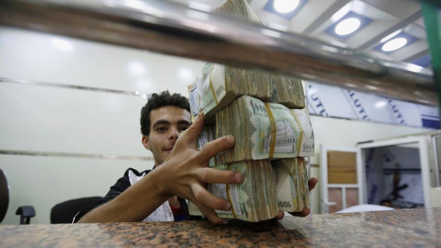 A money changer holds bundles of Yemeni currency at an exchange shop in Sanaa, Yemen, June 8, 2016. To match Insight YEMEN-SECURITY/CENBANK  REUTERS/Khaled Abdullah      TPX IMAGES OF THE DAY      - S1AETJAZJWAA