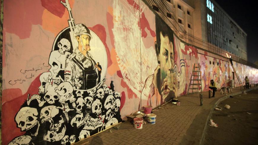 Artists, who are against the Egyptian army and government, work on graffiti representing anti-military power along Mohamed Mahmoud Street near Tahrir Square in Cairo early November 24, 2013. To commemmorate the passing of 100 days since security forces cleared the vigils in support of ousted President Mohamed Mursi in Cairo, supporters of the Muslim Brotherhood plan to take to the streets on Sunday. Army and police forces closed Rabaa al-Adawiya, Tahrir and Nahda squares in preparation for the demonstration