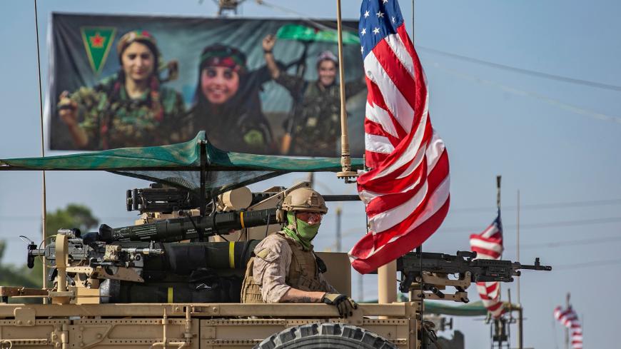 TOPSHOT - A US armoured vehicle drives past a billboard for the Syrian Kurdish Women's Protection Units (YPJ), during a patrol of the Syrian northeastern town of Qahtaniyah at the border with Turkey, on October 31, 2019. - US forces accompanied by Kurdish fighters of the Syrian Democratic Forces (SDF) patrolled part of Syria's border with Turkey, in the first such move since Washington withdrew troops from the area earlier this month, an AFP correspondent reported. (Photo by Delil SOULEIMAN / AFP) (Photo by