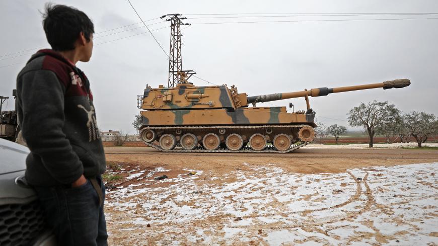 A child gazes at a Turkish 155mm self-propelled artillery gun in the town of Binnish in Syrias northwestern province of Idlib, near the Syria-Turkey border on February 12, 2020. - Tensions escalated yesterday between Syria's regime and rebel-backer Turkey as a Syrian military helicopter was shot down and Ankara warned of a "heavy price" for any attacks on its forces. (Photo by Omar HAJ KADOUR / AFP) (Photo by OMAR HAJ KADOUR/AFP via Getty Images)