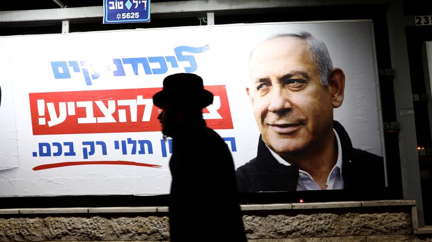 An ultra-Orthodox Jewish man walks past a Likud election campaign poster depicting Israeli Prime Minister Benjamin Netanyahu, in Jerusalem February 25, 2020. REUTERS/Ammar Awad - RC2V7F9VCDA1